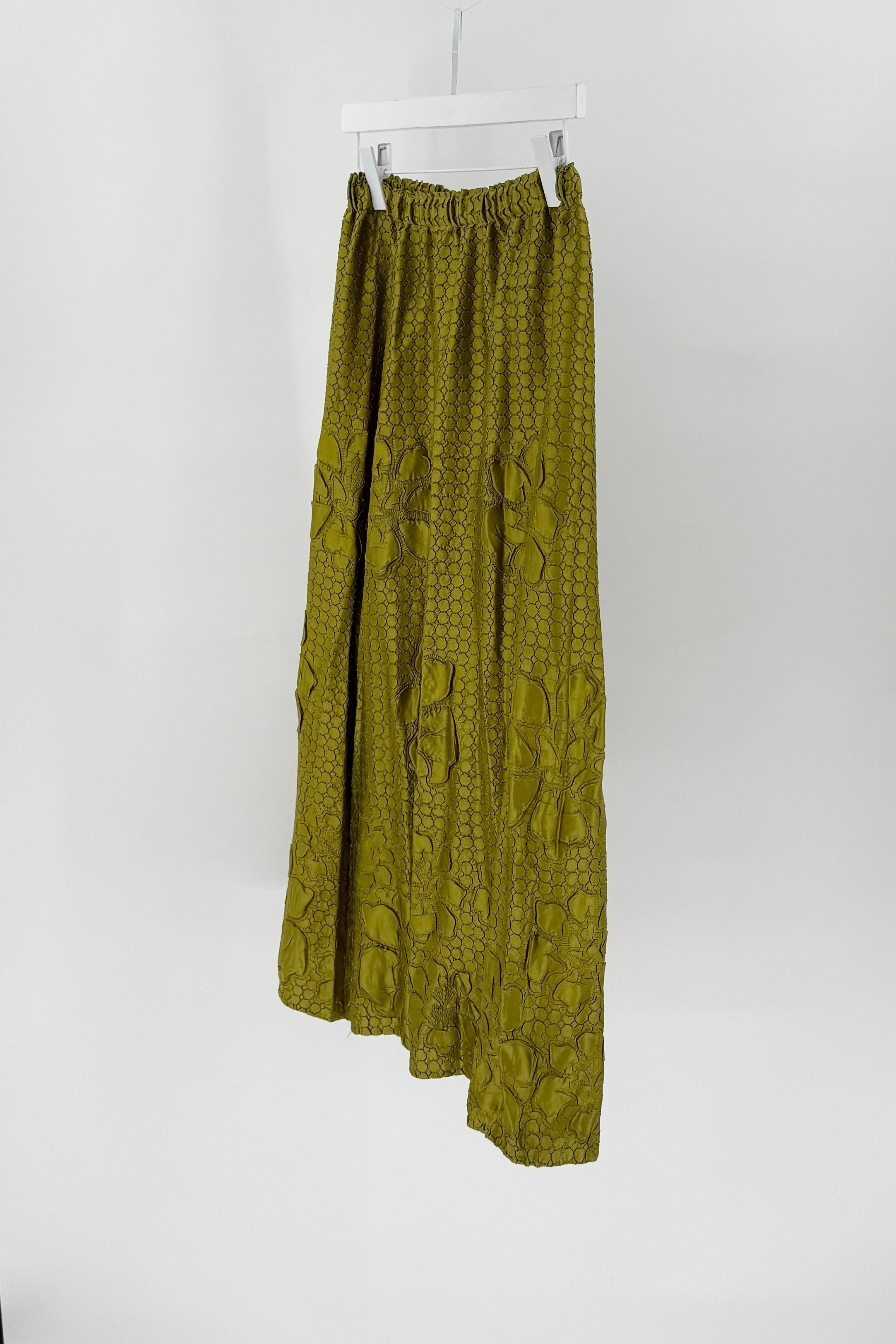 Green patterned skirt hanging on a white background