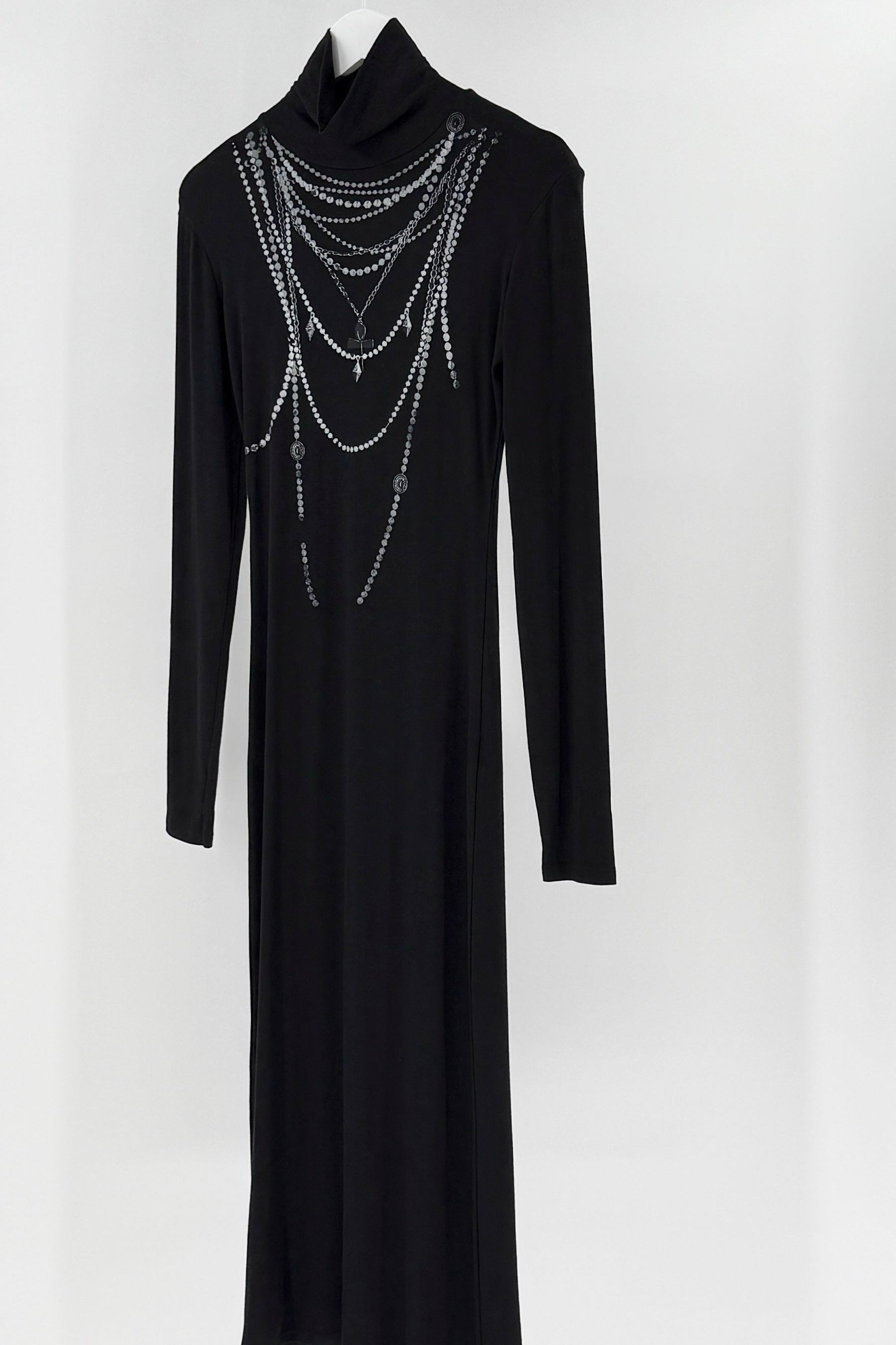 Black dress with long sleeves and printed decorative chain details on a white background