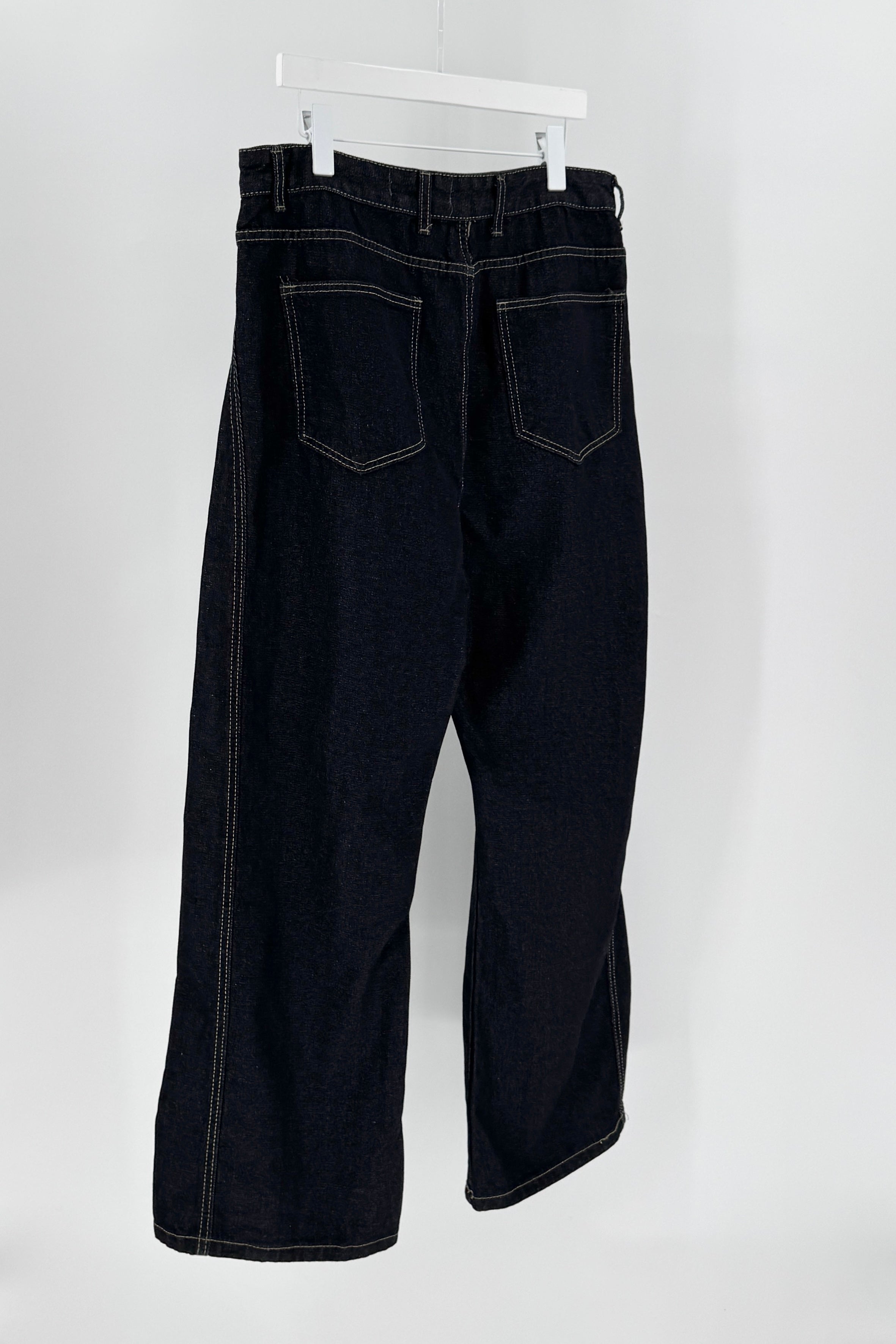 Black jeans hanging on a white hanger against a white background