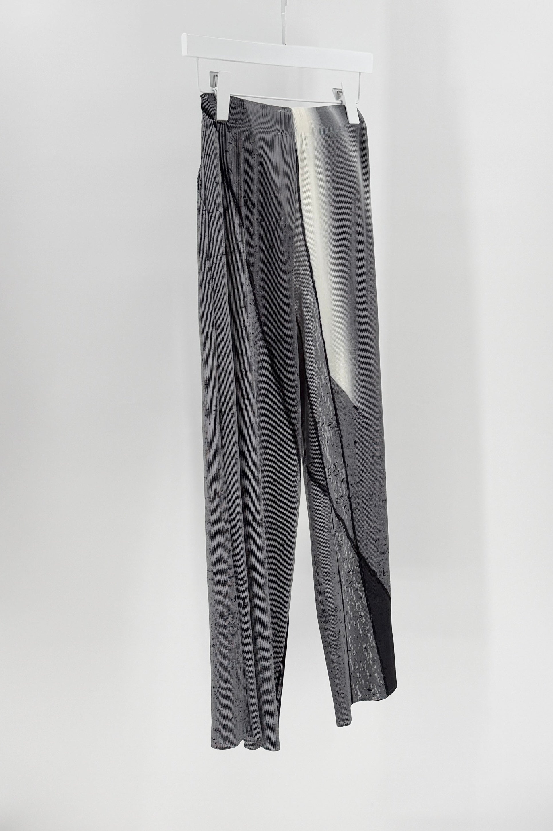 Gray textured pants hanging on a white background