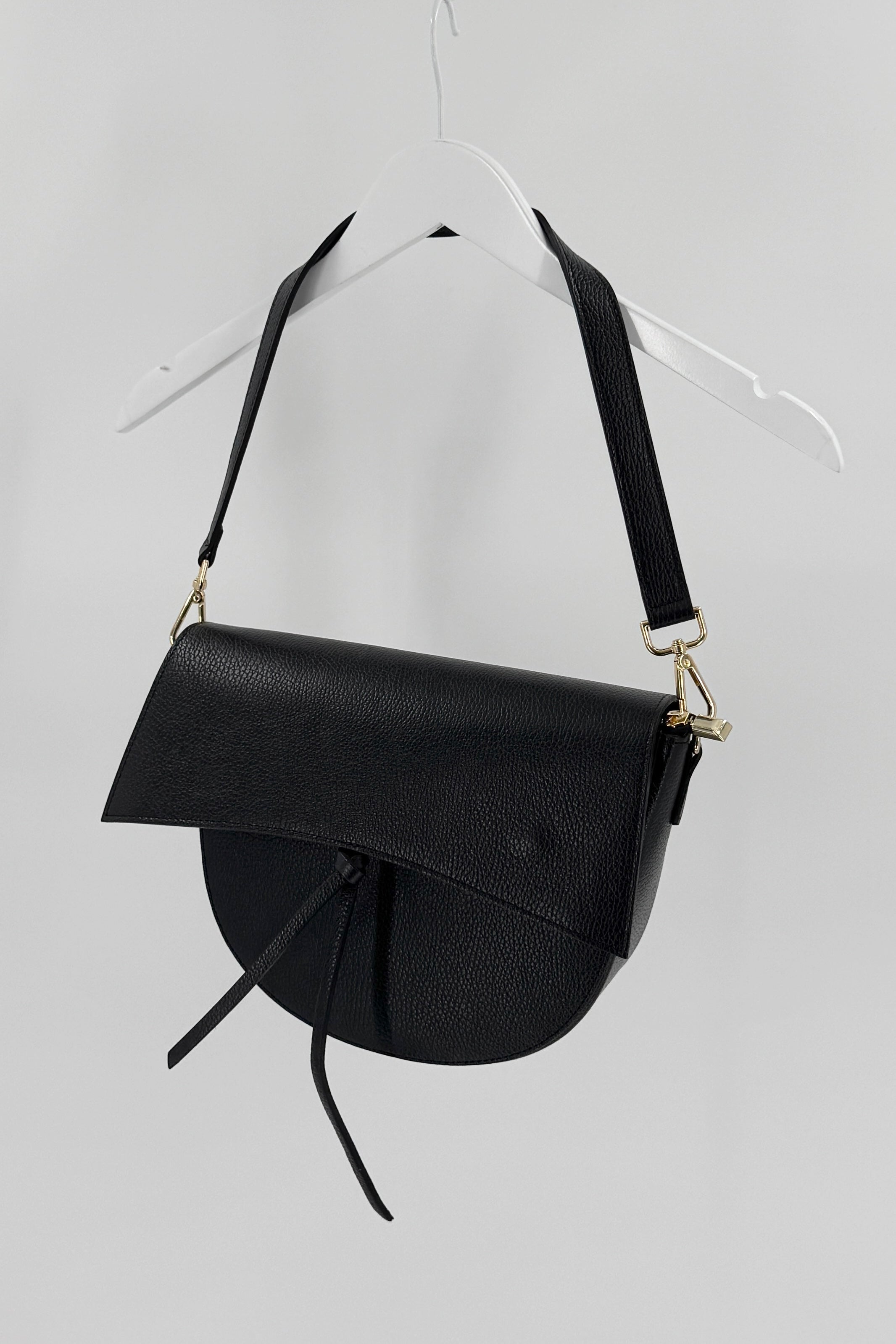 Black handbag with a strap on a light gray background