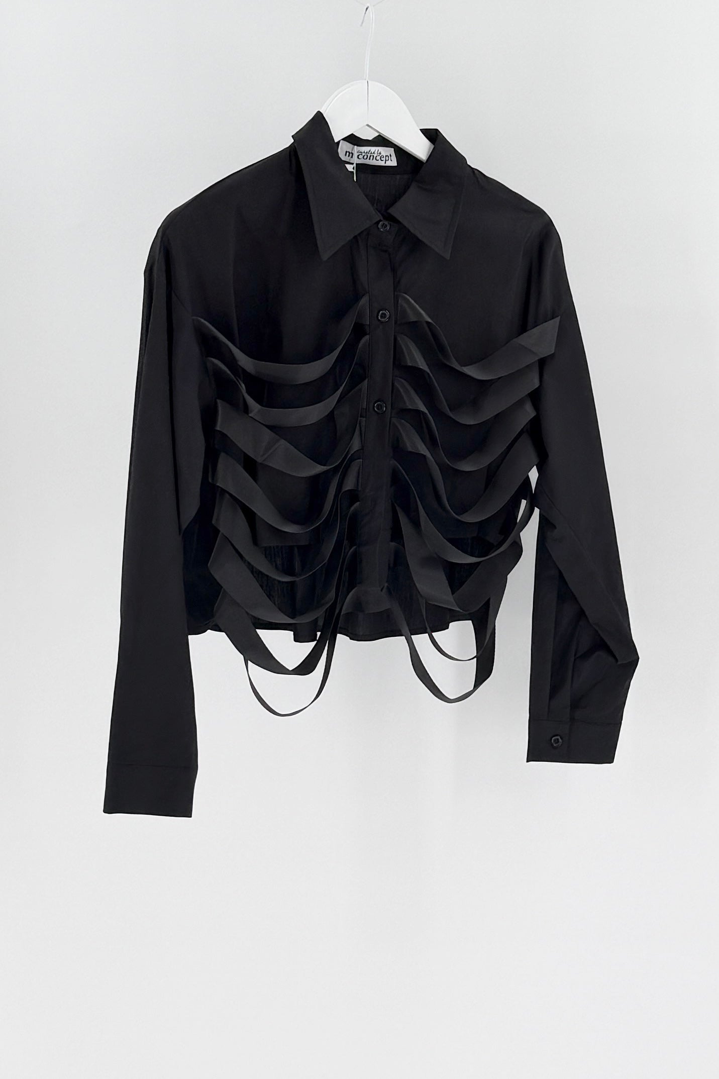 Black ruffled blouse on a white hanger against a white background