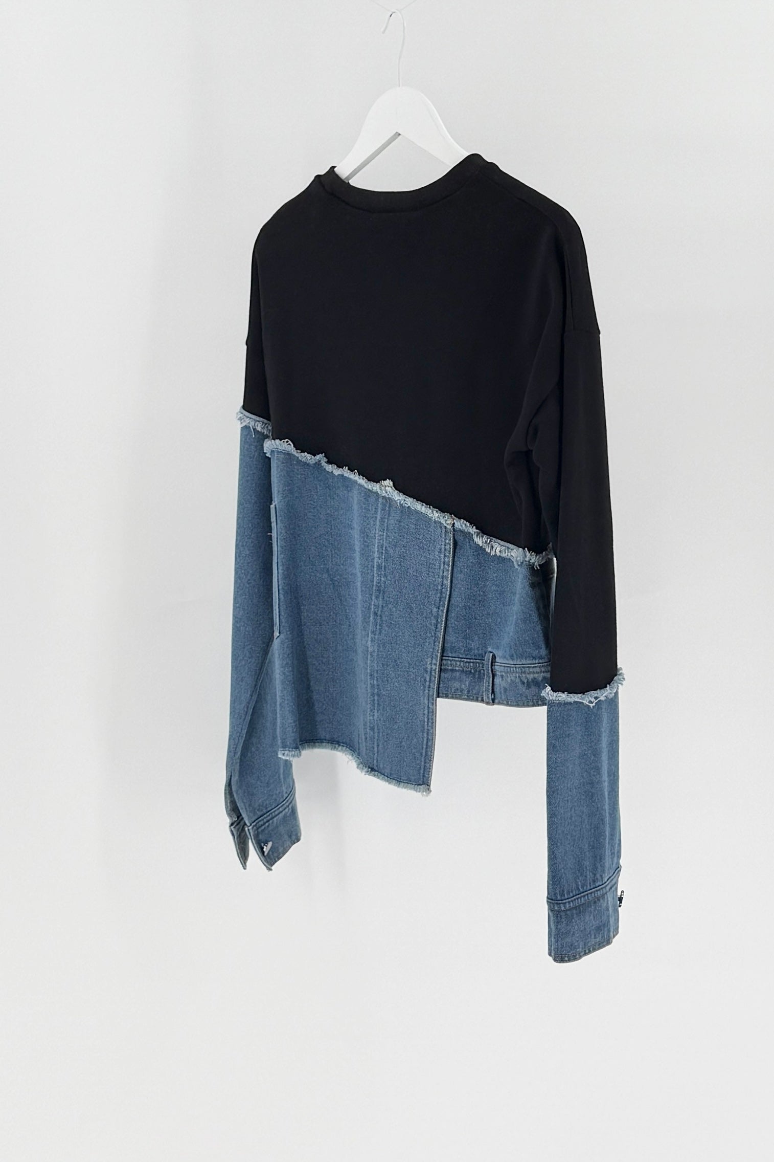 Black long-sleeve shirt with denim sleeves on a white hanger against a white background