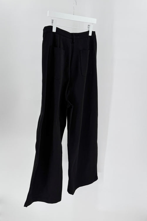 Black pants hanging on a white hanger against a white background