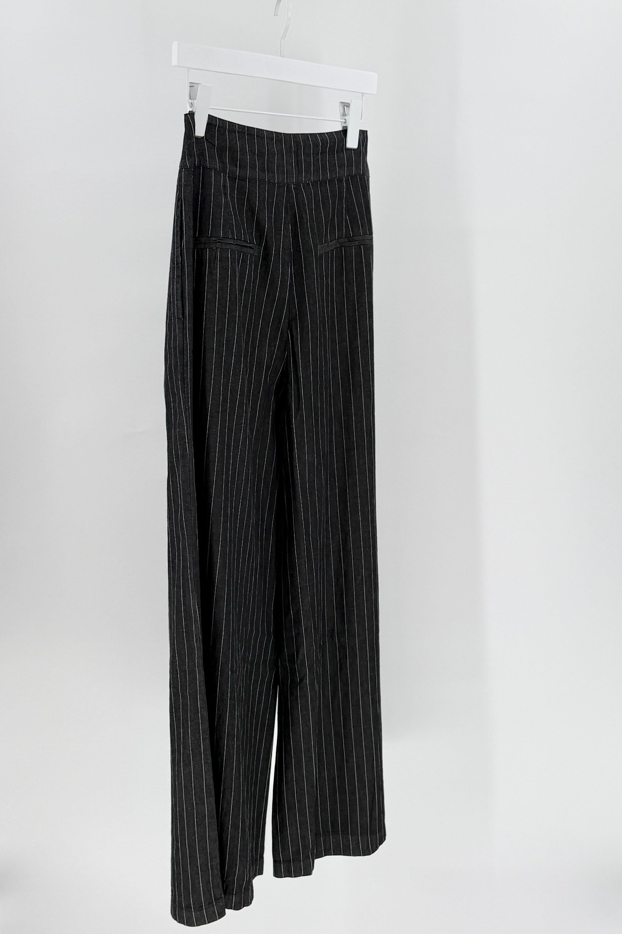Black pinstripe pants on a white hanger against a white background
