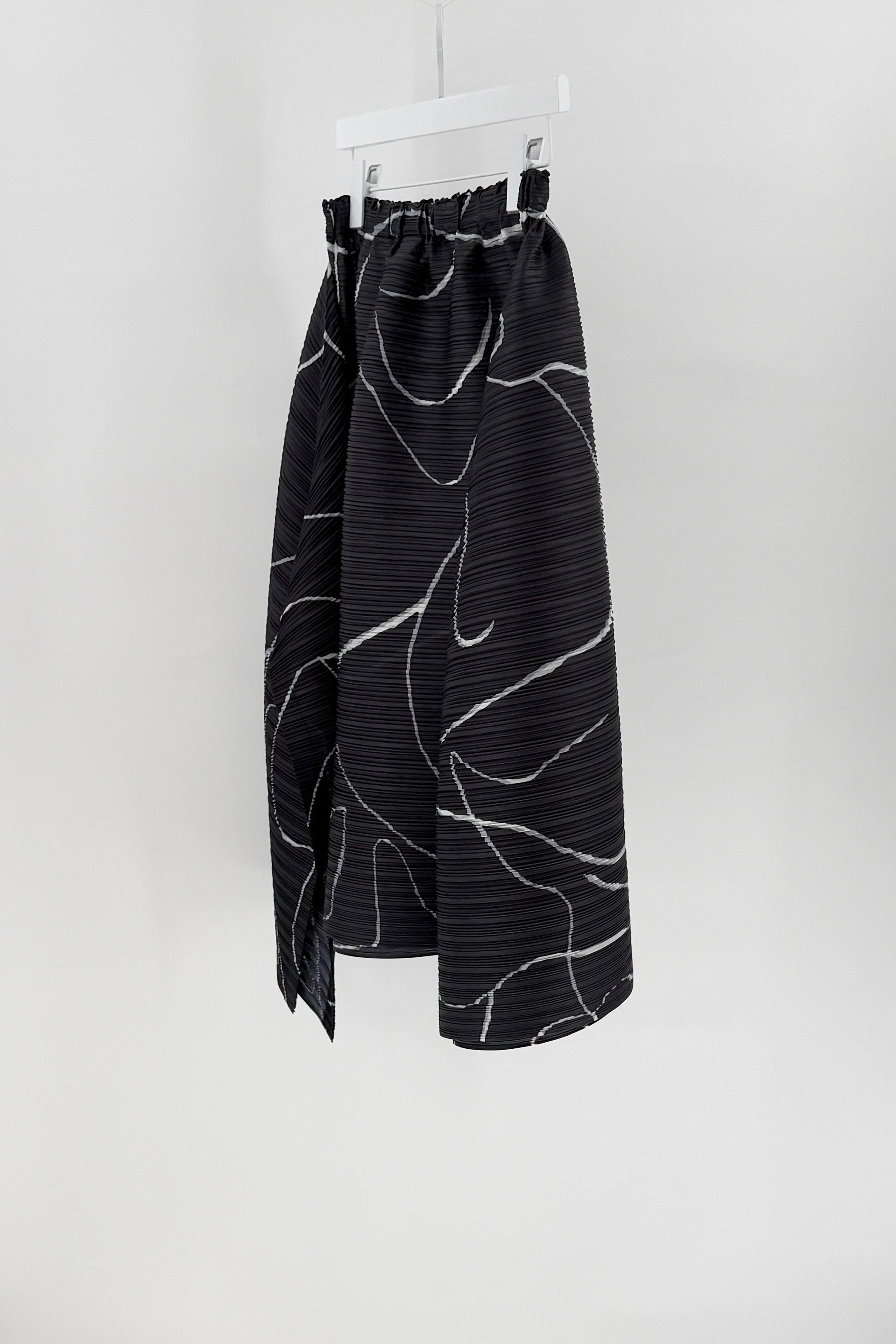 Black skirt with white abstract patterns on a hanger against a white background