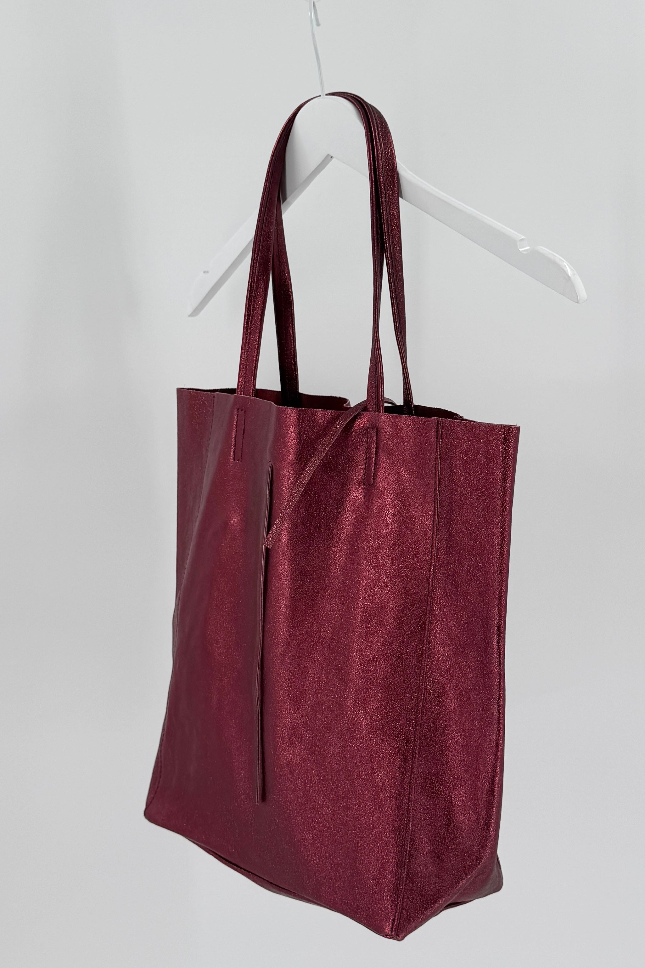 Maroon tote bag on a white hanger against a white background