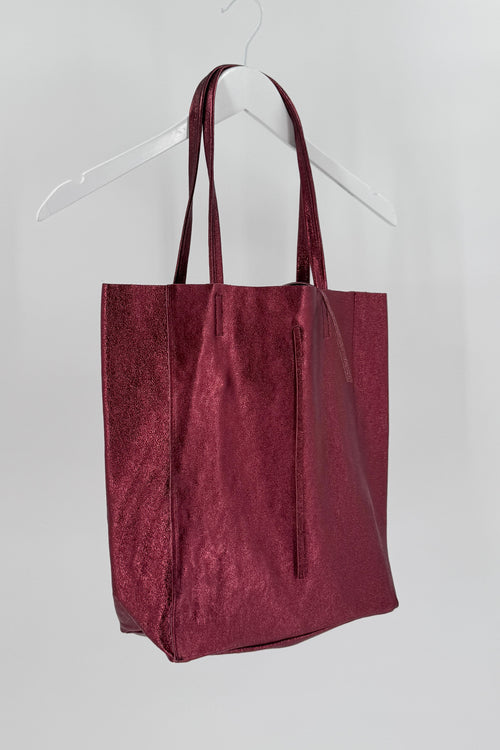 This is a metallic red bag on a white background suspended from a white hanger.