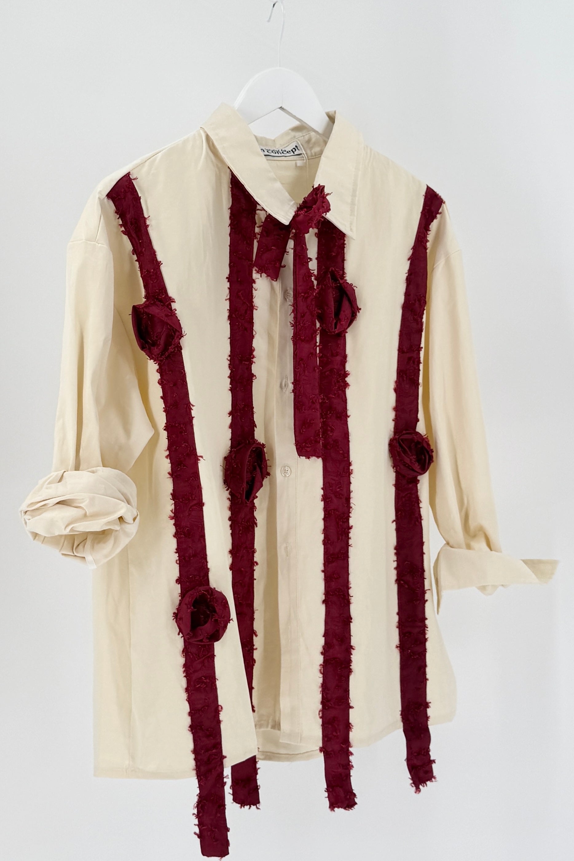 Cream-colored shirt with burgundy rose details on a white background
