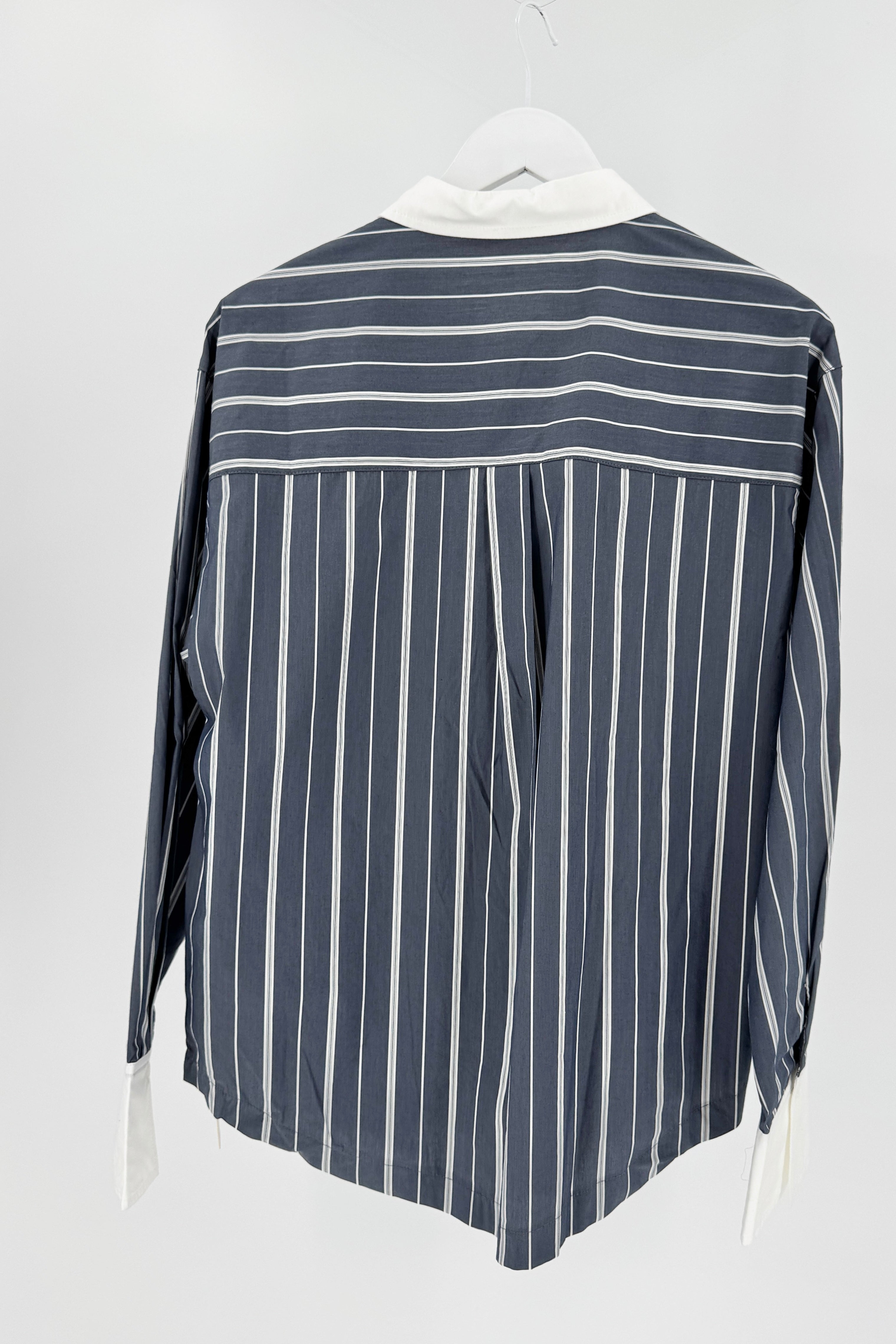 This is the back view of a striped shirt with white collar and cuff against a white background on a hanger.