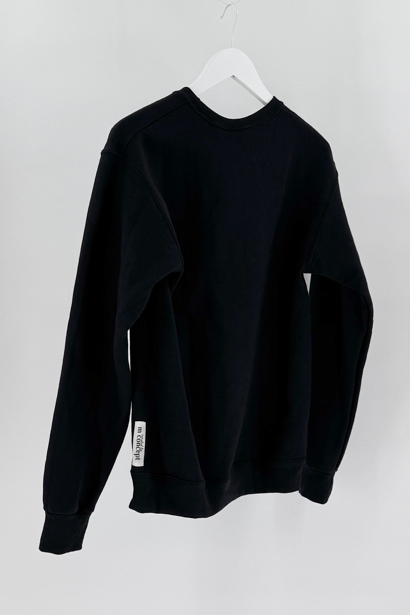 Black sweatshirt on a white hanger against a white background